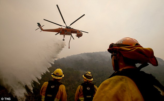 Trực thăng phun nước và lính cứu hỏa được huy động toàn lực nhằm ngăn chặn đám cháy lây lan rộng hơn. (Ảnh: TNS)
