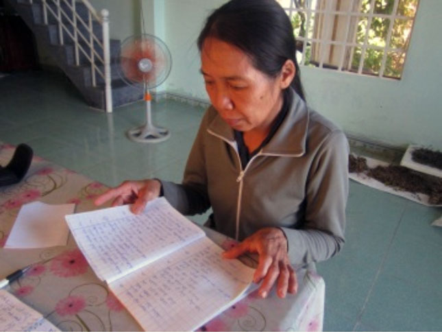 Chị Trần Thị Yến với cuốn vở ghi danh sách các liệt sĩ.