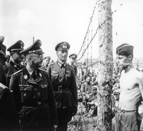 Binh sĩ Anh (cởi trần) nhìn thẳng vào mặt trùm mật vụ phát xít Heinrich Himmler khi hắn đi thị sát một nhà tù. Ảnh: AP