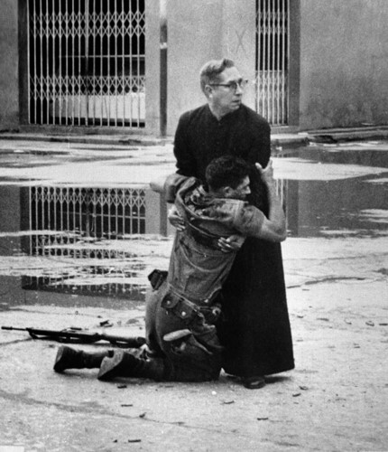 Cha Luis Manuel Padilla ôm một binh sĩ quân chính phủ Venezuela bị thương tên đường phố Puerto Cabello vào tháng 6/1962. Bức ảnh này đã đem lại giải Putlizer cho tác giả Hector Rondon. Ảnh: AP