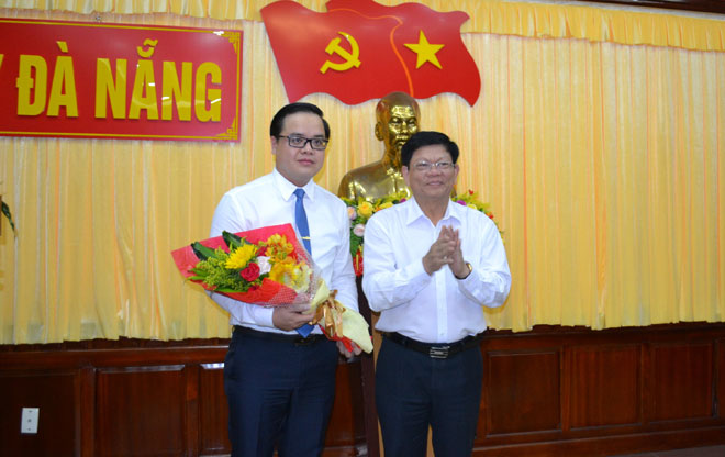 Phó Bí thư Thường trực Thành ủy Võ Công Trí (bên phải) tặng hoa chúc mừng ông Trần Nguyễn Minh Thành 