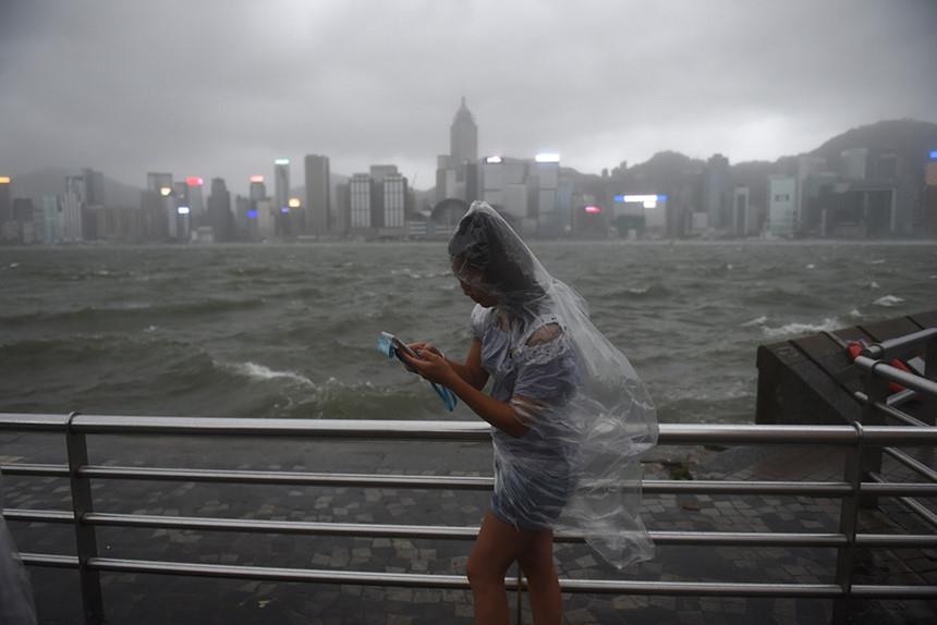 Bão Hato đã suy yếu và tiếp tục di chuyển theo hướng Tây - Tây Bắc. Trong ảnh, người phụ nữ Hong Kong đi bộ bên vịnh Victoria trong cơn mưa tầm tã. Ảnh: Reuters.