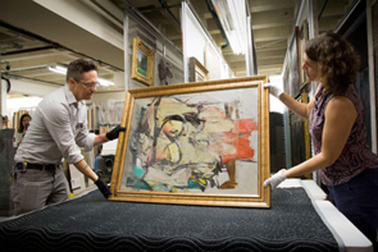 Nathan Saxton (trái) và Kristen Schmidt, chuyên viên của UAMA-Bảo tàng Nghệ thuật Đại học Arizona đặt bức  “Woman-Ochre” lên bàn để kiểm tra. 