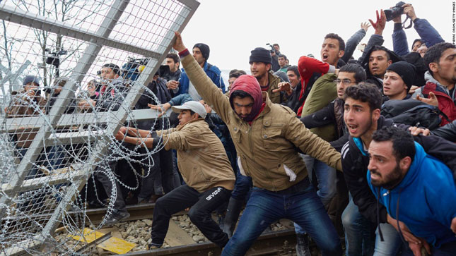 Những người tị nạn cố vượt qua hàng rào ở biên giới Hy Lạp - Macedonia hồi tháng 2-2016. 							                      Ảnh: CNN