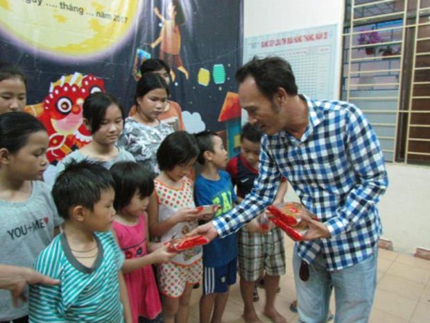 Mr Tran Ngoc Cuong (right) presenting mooncakes to children who are living in the city's Care Centre for Street Children  