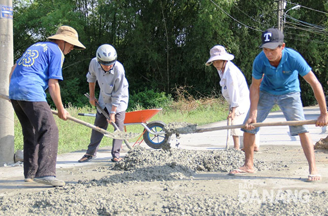 Trưởng thôn Trà Kiểm Nguyễn Thanh Quý (thứ hai, từ trái sang) đang cùng người dân trộn bê-tông sửa lại đường kiệt, hẻm.