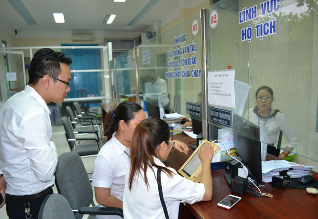 Người dân được hướng dẫn sử dụng máy tính bảng để đánh giá mức độ hài lòng sau khi giao dịch hành chính tại UBND phường Hòa Thuận Tây. 