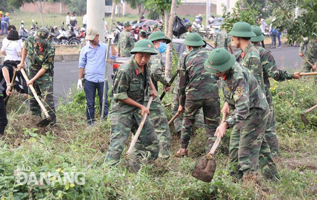 Cán bộ, chiến sĩ thuộc các lực lượng vũ trang trên địa bàn thành phố phát quang bụi rậm, thu gom rác. 							       Ảnh: QUỐC KHẢI