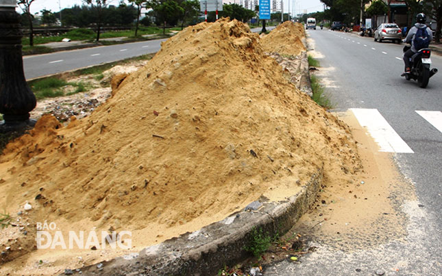 Nhiều đống đất được đổ 2 tuần nay đang chảy xuống lòng đường. Ảnh: HOÀNG HIỆP