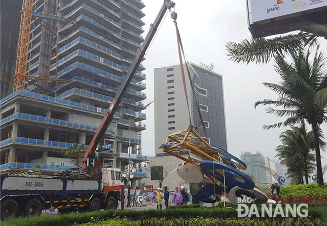 Ngay trong mưa lớn, gió mạnh, lực lượng chức năng huy động nhân lực và phương tiện khắc phục sự cố sập cổng chào trang trí ở đường Võ Nguyên Giáp.  Ảnh: HOÀNG HIỆP