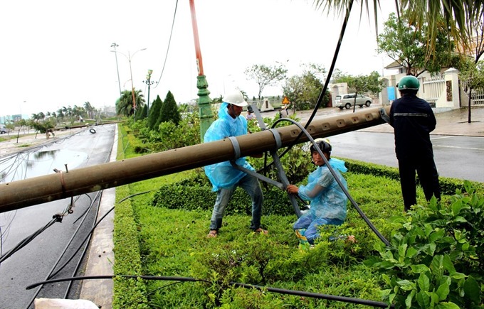 Electricity workers in Phú Yên Province repair an electricity pole that collapsed in Tuy Hòa City on Saturday. — VNA/VNS Photo Thế Lập Read more at http://vietnamnews.vn/society/416915/typhoon-damrey-leaves-29-dead-29-missing.html#7sqVMl01j5hczg74.99