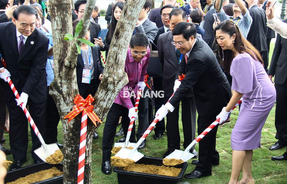 Phó Thủ tướng, Bộ trưởng Ngoại giao Phạm Bình Minh và đại biểu các nền kinh tế thành viên APEC thực hiện hiện nghi thức trồng cây xanh tại Công viên APEC 2017. Ảnh: QUỐC KHẢI. 