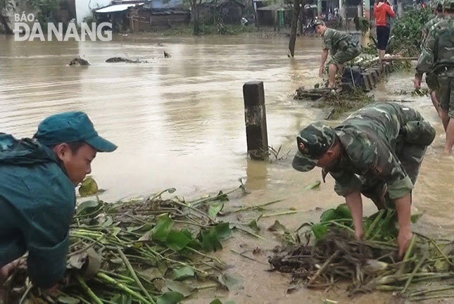 Men from the Military School of Military Region 5 clearing rubbish along flooded HD 409 Street   