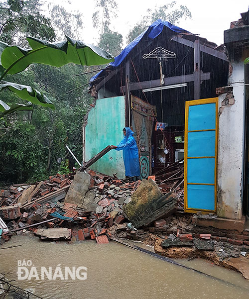 Ông Đặng Quy Thành thu dọn một vài vật dụng sau khi gần nửa căn nhà bị đổ sau lũ lớn.