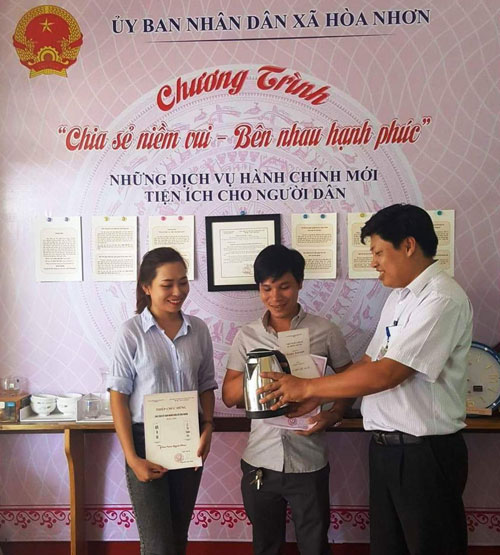 Đại diện chính quyền xã Hòa Nhơn (phải) trao Giấy đăng ký kết hôn và quà mừng cho vợ chồng anh Phạm Tấn Hải và chị Nguyễn Trần Mỹ Lệ Thu.