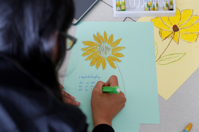 A student from Đà Nẵng’s Đông Á college paints a sunflower to raise money for kids with cancer at hospitals in Đà Nẵng. — VNS Photo Công Thành Read more at http://vietnamnews.vn/life-style/418134/ba-na-hills-to-host-christmas-celebration.html#CwQ0xyJhtSJZ2smW.99