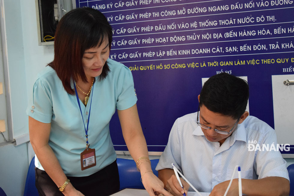 An employee from the Son Tra District PC’ ‘one-stop-shop’ mechanism (left) helping a citizen compete his dossiers