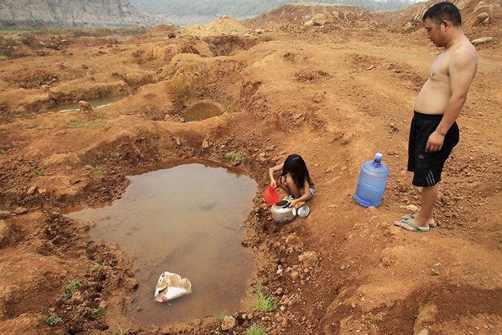 Hai cha con đang cố lấy nước từ vũng nước tại một hồ trữ nước đã bị cạn khô ở huyện Bảo Phong, tỉnh Hà Nam (Trung Quốc).