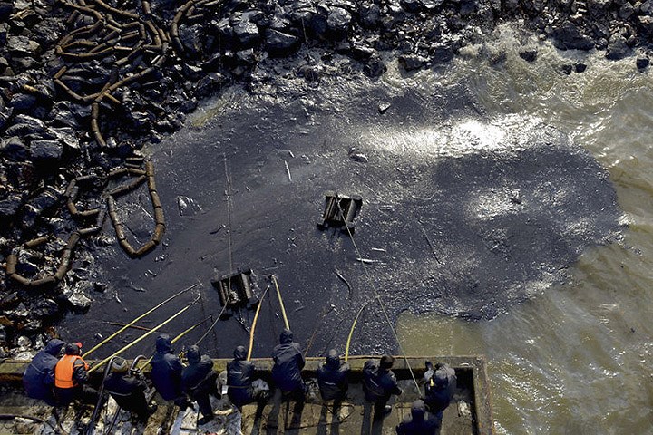 Công nhân dọn dầu rò rỉ sau một vụ nổ ống dẫn dầu ở thành phố Thanh Đảo, tỉnh Sơn Đông.