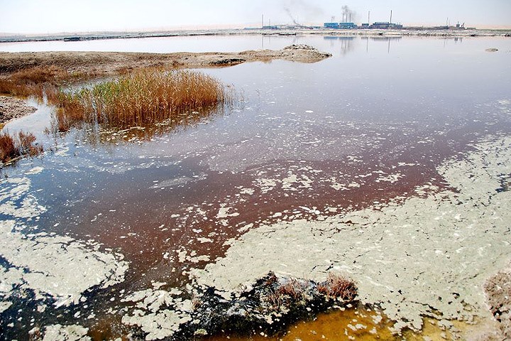   Một hồ nước ô nhiễm nặng khác của Trung Quốc. Phía xa là một nhà máy đang nhả khói đen.
