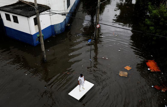 Một người đàn ông sử dụng mặt bàn để lướt trên đường ngập nước sau trận mưa lớn ở Sao Paulo, Brazil ngày 7/4.
