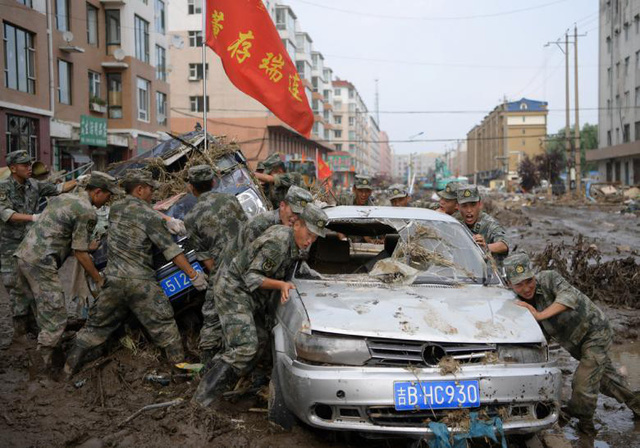 Lực lượng cứu hộ tìm cách đưa những chiếc xe bị hư hại ra khỏi đống đổ nát và bùn lầy sau trận bão ở tỉnh Cát Lâm, Trung Quốc ngày 17/7.