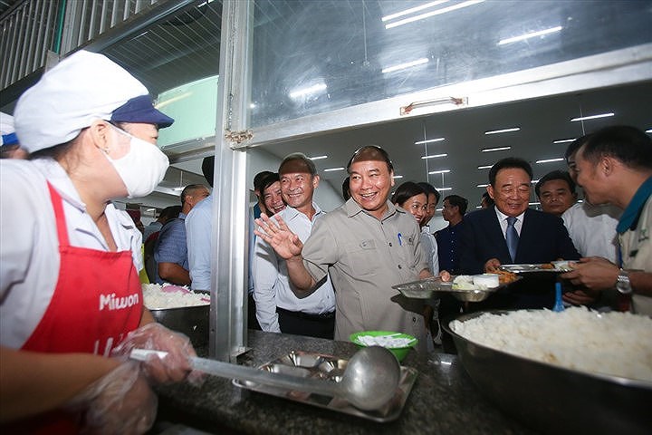 Sau khi xem qua thực đơn gồm cơm, thịt kho, rau xào, canh và sữa chua, Thủ tướng đã lấy riêng cho mình một phần cơm rồi ngồi cùng ăn cùng hàng trăm công nhân.  (Ảnh: Lao Động)