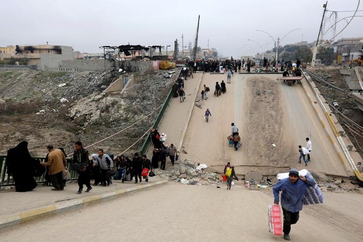 Người dân chạy trốn giặc IS vượt qua một cây cầu bị sập ở khu Al-Muthanna của Mosul, Iraq vào ngày 15-1.