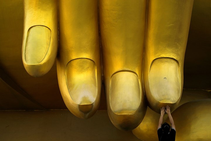 Một phụ nữ Thái Lan cầu nguyện trước ngón tay bằng vàng của một bức tượng Phật. Ảnh: Reuters