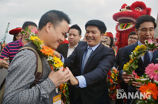 Giám đốc Sở Du lịch, ông Ngô Quang Vinh (giữa), tặng hoa chúc mừng vị khách tàu biển đầu tiên đặt chân đến Đà Nẵng dịp đầu năm mới. Ảnh: THU HÀ