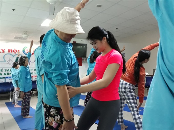 Đặng Thị Quỳnh Như (centre) adjusts body position for a cancer patient in her free yoga therapy class at the Đà Nẵng City General Hospital. - Photo thanhnien.vn Read more at http://vietnamnews.vn/society/420623/yoga-trainer-eases-cancer-patients-pain.html#gbQGFZwRvUOROBrV.99