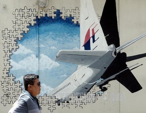 A Malaysian man walks in front of a mural of missing Malaysia Airlines MH370 plane in hah Alam, Malaysia on March 8, 2016. (Photo: AFP/VNA)