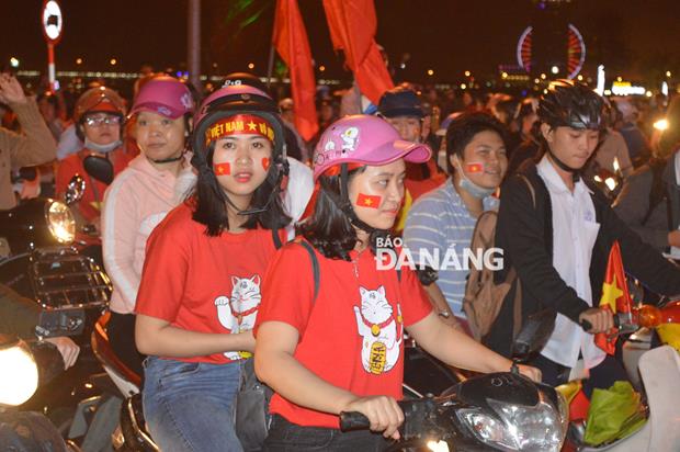 Small national flags and other decoration patterns painted on the cheeks of young fans