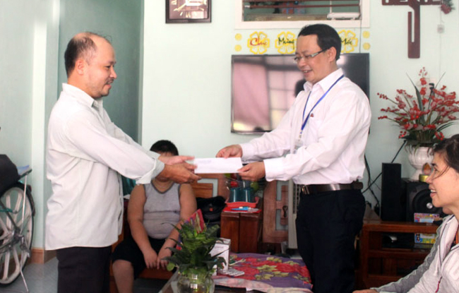 Trưởng phòng Tư pháp quận Cẩm Lệ Trần Trung Thanh (phải) tặng quà cho gia đình trẻ em bị bệnh hiểm nghèo trên địa bàn quận.