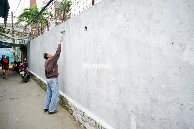 A local resident is helping painters cleaning a wall