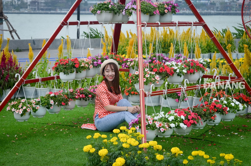  A young lady posing for a souvenir photo with beautiful Tet flowers