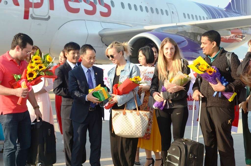 Ông Nguyễn Xuân Bình, Phó giám đốc Sở Du lịch Đà Nẵng (thứ 2 từ trái sang) đang tặng hoa và quà chúc mừng những vị khách quốc tế đầu tiên đến Đà Nẵng dịp đầu xuân năm mới