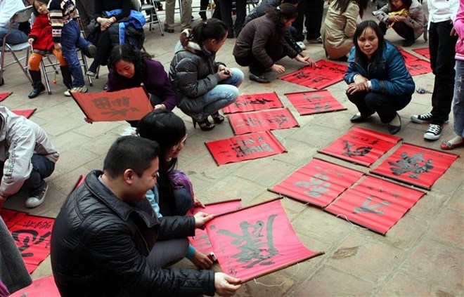 People look at the calligraphic words at the Quoc Tu Giam (Imperial Academy) (Photo: VNA)