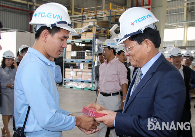 Phó Bí thư Thường trực Thành ủy Võ Công Trí (bên phải) tặng quà đầu năm cho cán bộ, nhân viên Công ty TNHH TCIE Việt Nam. Ảnh: Trâm Anh