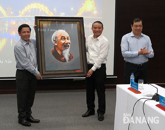 Secretary Nghia (centre) presenting a momento to Minister The (left)