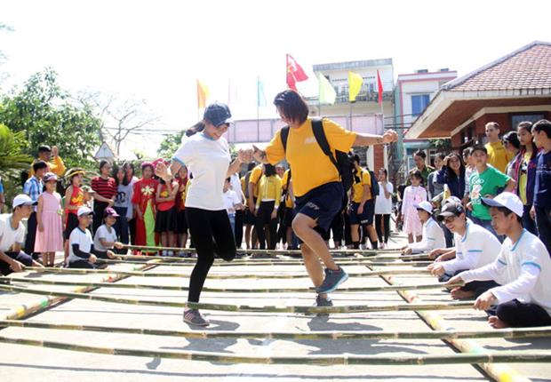 A US guest (in yellow T-shirt) dancing with bamboo poles with children at the SOS village …