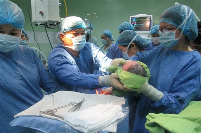 Director of Đà Nẵng Hospital for Women and Children Trần Đình Vinh (centre) and medical workers deliver the first baby born through IVF at the hospital in late 2014. — Photo laodong.vn Read more at http://vietnamnews.vn/society/423948/doctors-help-infertile-couples-with-ivf.html#8TKIOSP6kZp77xhG.99