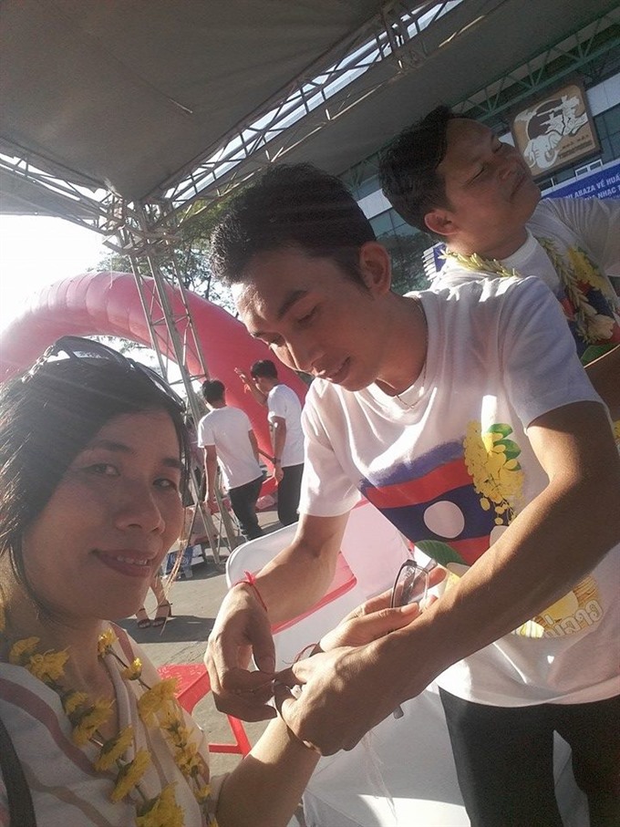 A thread is tied on the wrist of a visitor at the traditional Laos New Year in Đà Nẵng. — VNS Photo Ngọc Tăng Read more at http://vietnamnews.vn/life-style/424312/laos-day-to-open-at-da-nang-museum.html#wYKVWm9Phj2oK0xX.99