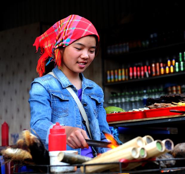  An ethnic H'mong girl preparing some traditional cuisines to serve visitors