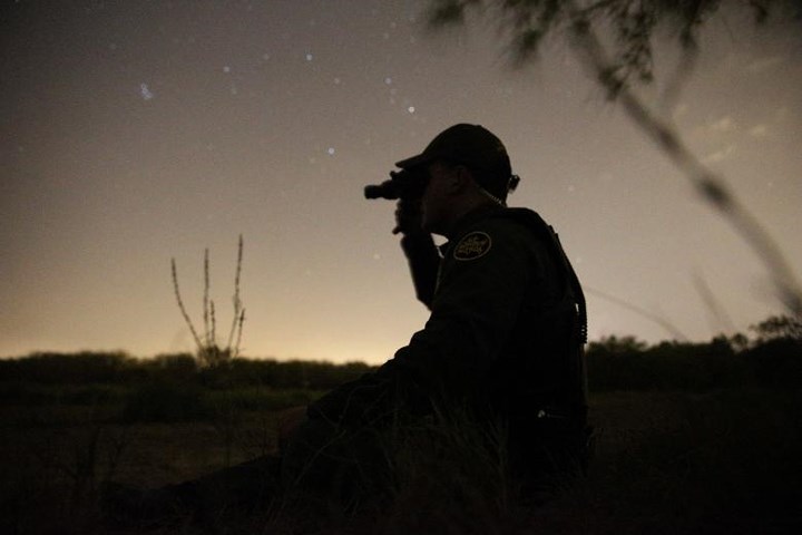 Một nhân viên tuần tra biên giới sử dụng kính nhìn đêm để tìm kiếm những người nhập cư bất hợp pháp vượt biên từ Mexico vào Mỹ.