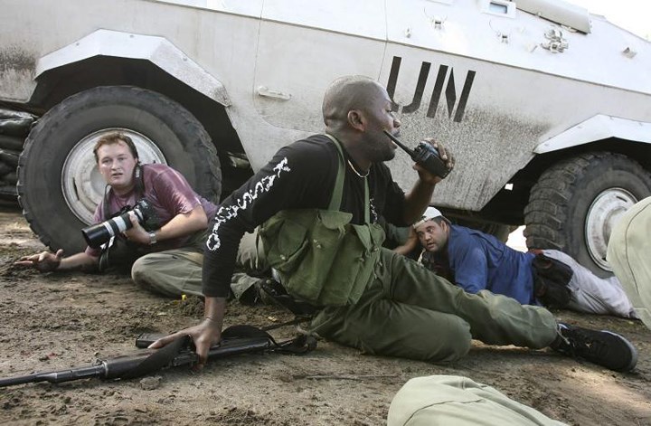 Phóng viên của Reuters (trái) nấp dưới một xe bọc thép của Liên Hợp Quốc trong một cuộc giao chiến bằng súng máy và súng cối ở Kinshasa, CHDC Congo vào tháng 11/2006.