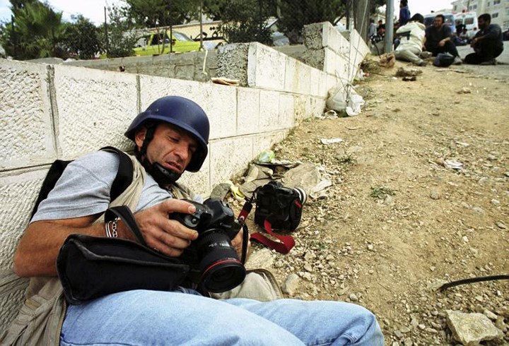 Nhà báo người Hy Lạp Behrakis đang nấp khi xảy ra đấu súng giữa quân Israel và các chiến binh Palestine ở thành phố Ramallah vào tháng 3/2001.
