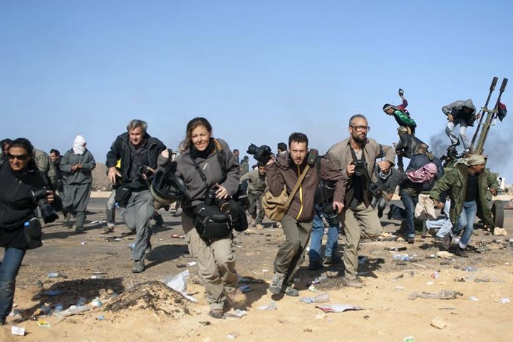 Các nhà báo đang vội vã tìm nơi trú ẩn khi có loạt bom ném từ máy bay ở một chốt kiểm soát gần mỏ dầu Ras Lanuf ở Libya vào tháng 3/2011.