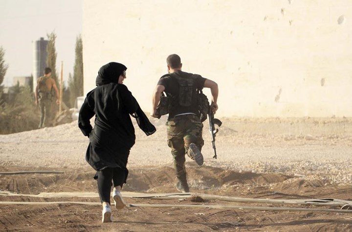 Một nữ phóng viên bám theo một phiến quân lúc họ tránh hỏa lực bắn tỉa ở ngoại ô Aleppo (Syria) vào ngày 10/10/2014./.