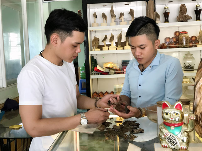 Nguyễn Vũ Tra (bên phải) giới thiệu với khách hàng về các sản phẩm trầm hương của mình. Ảnh: T.N